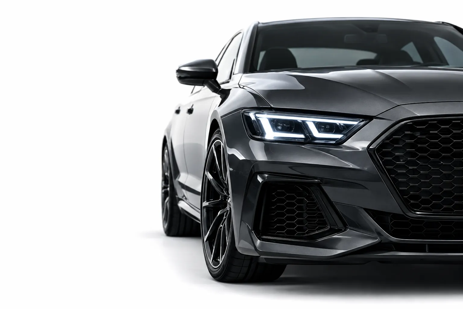 Dark grey sports sedan front end with sharp LED headlights on a white background